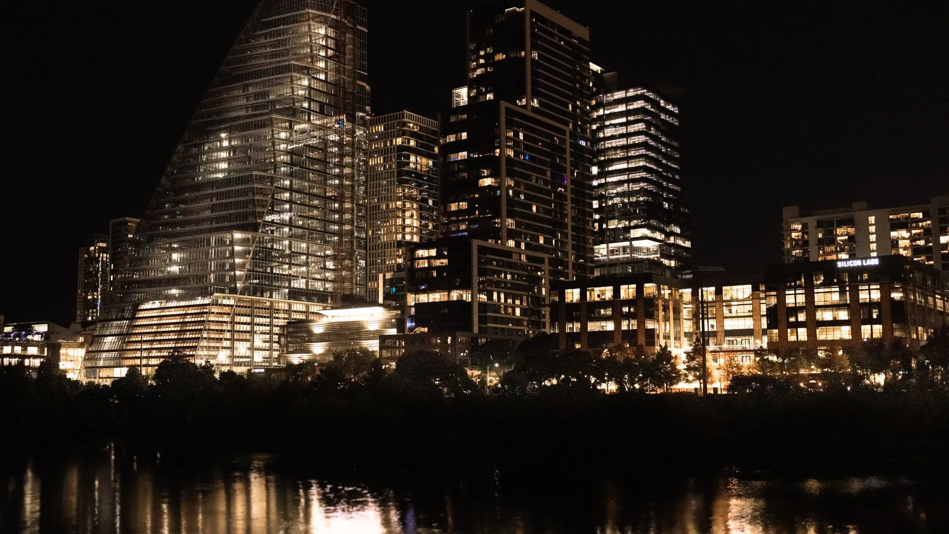 Illuminated skyscrapers reflecting in the river at night in downtown