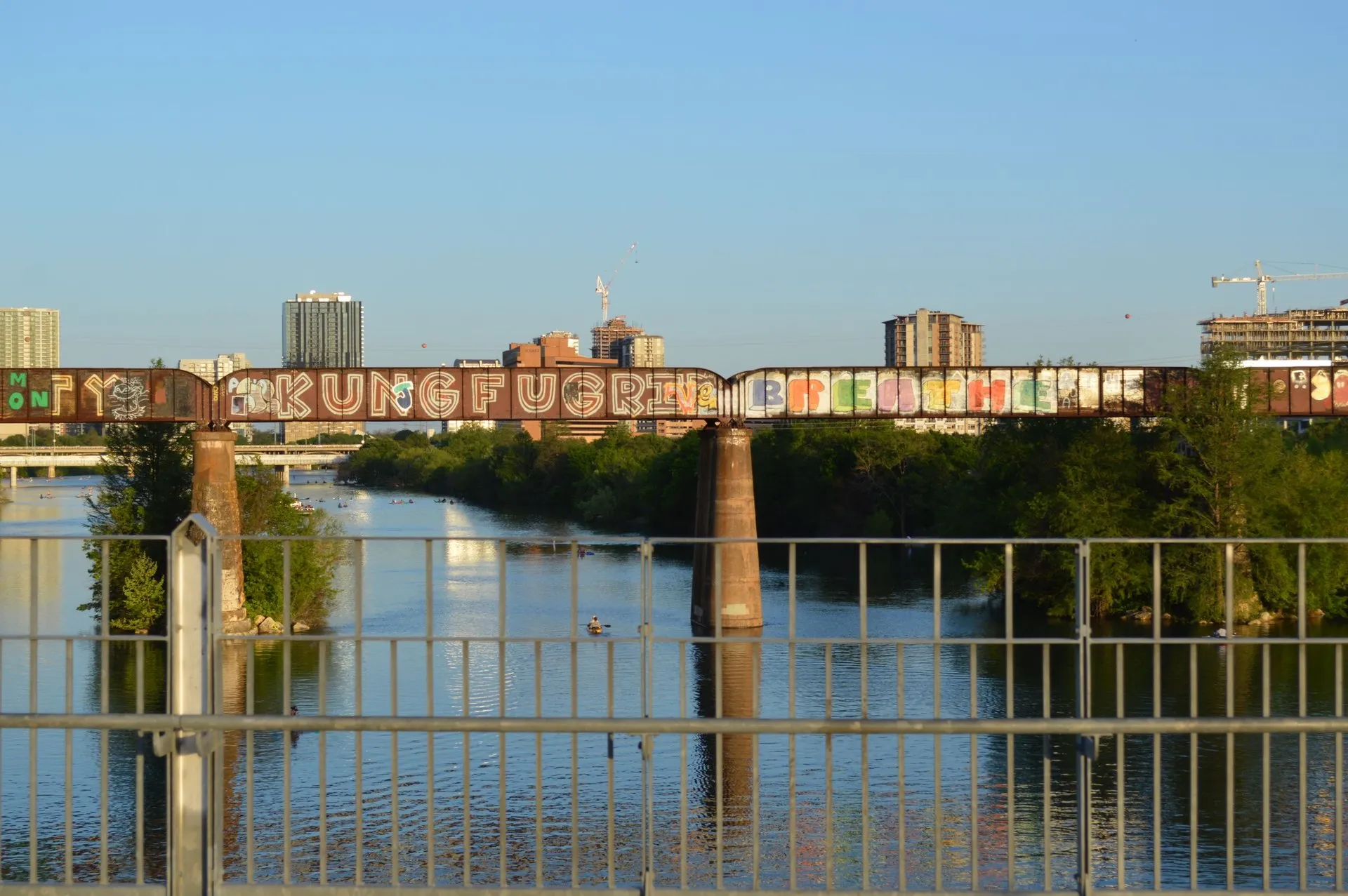 Colorful graffiti on a bridge over Lady Bird Lake with Austin skyline