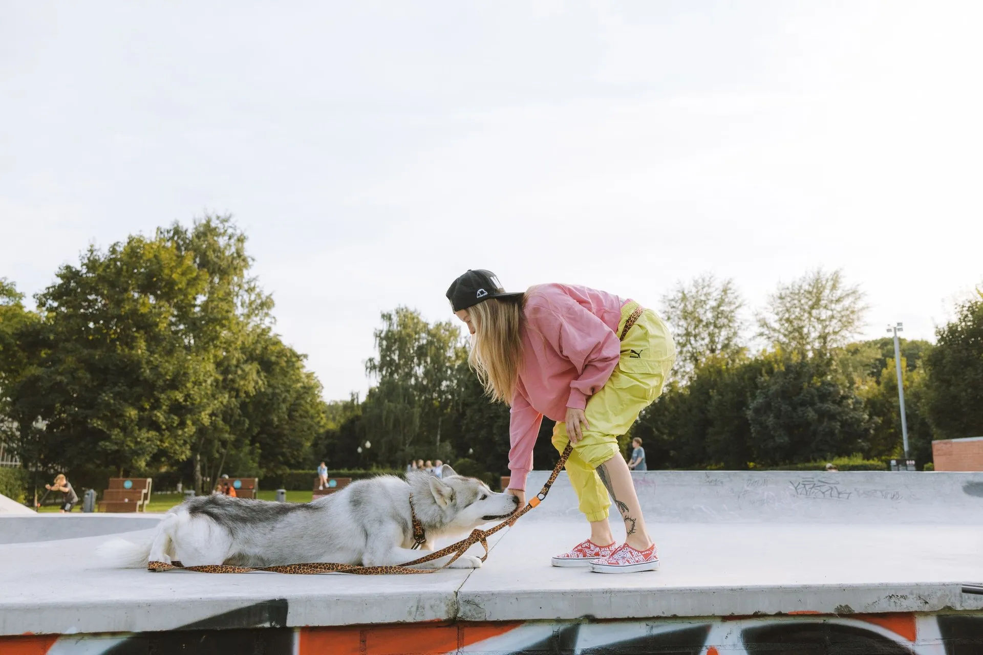 A young woman playfully bends over to interact with her Siberian Husky