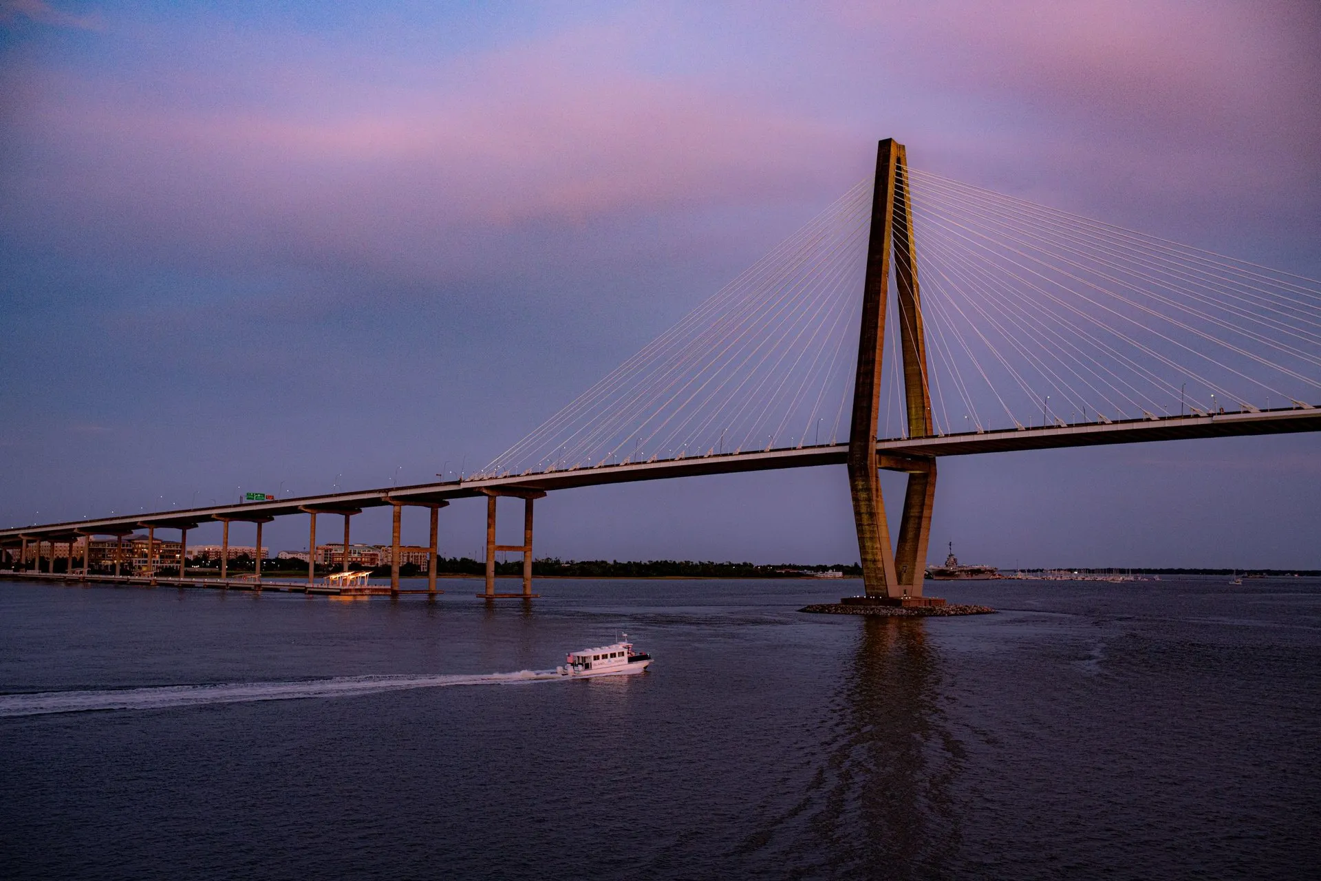 View of Charleston's Arthur Ravenel Jr. Bridge at sunset with a boat
