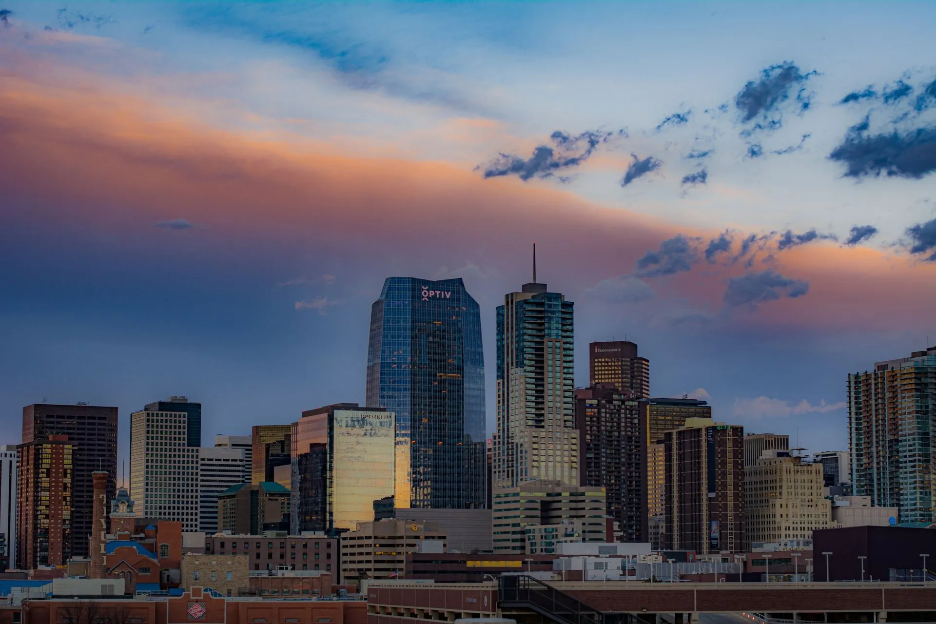 View of Denver's cityscape with skyscrapers under a colorful sunset sky