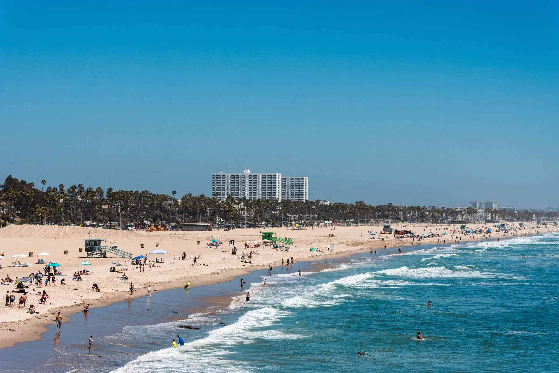 People enjoying a sunny day on Santa Monica Beach with a vibrant blue