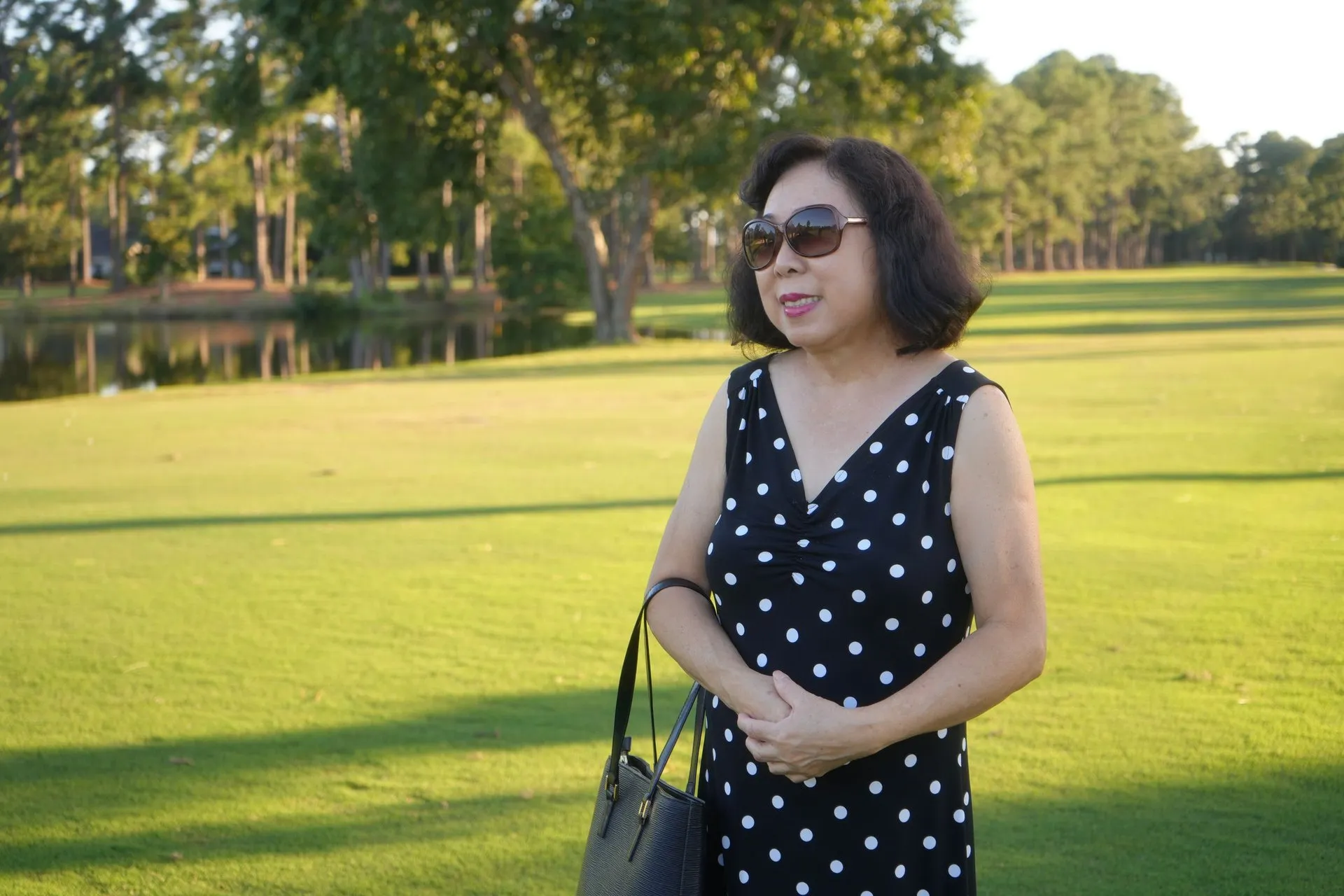Elegant woman in sunglasses and polka dot dress enjoying sunny day at