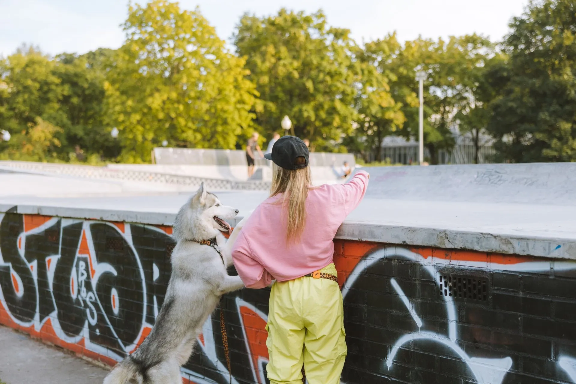 A woman and her Husky dog standing together at an urban skatepark