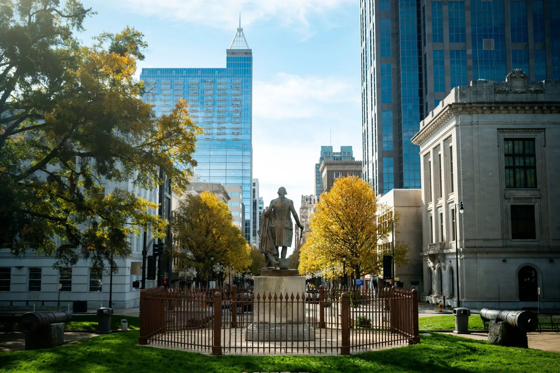 Statue in downtown Raleigh with skyscrapers and fall foliage