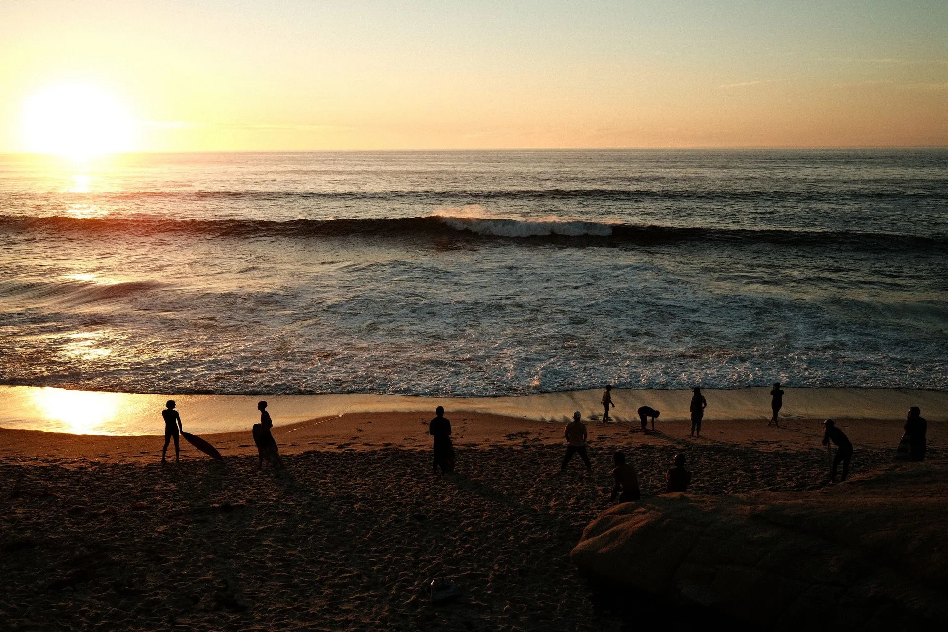 A mesmerizing sunset scene with silhouettes of people on a San Diego beach
