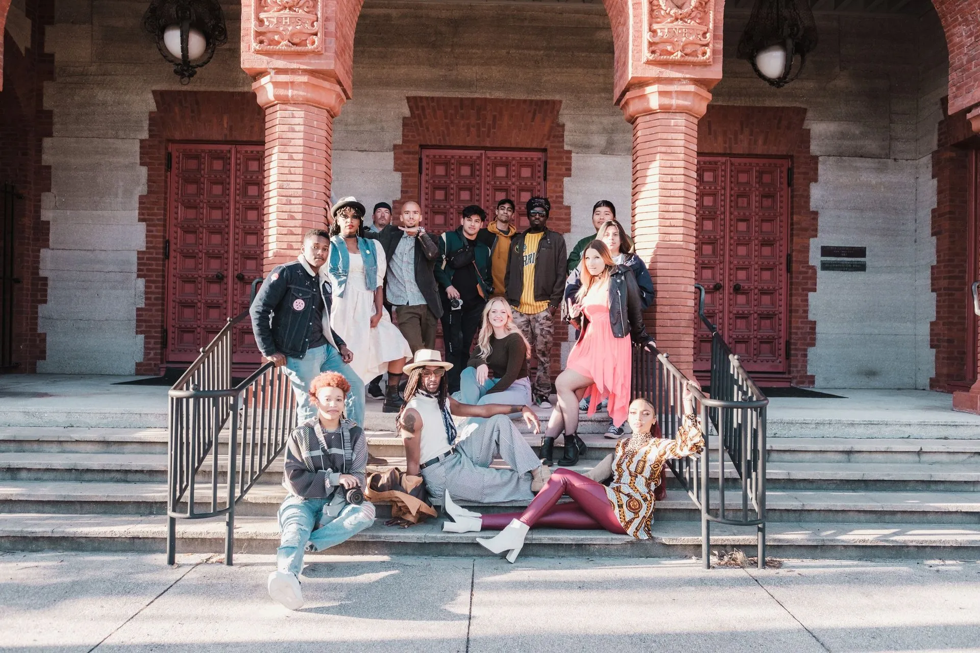 A diverse group of adults posing on steps of a historic building in St.